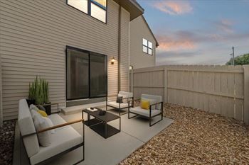 A modern outdoor patio with a couch, chairs, and a table.